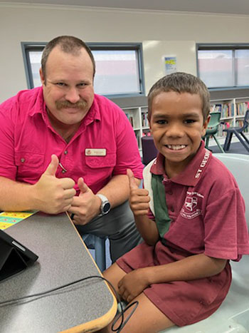 Photo of a teacher and a student sitting around a table in a school library.