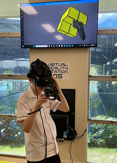 Student using the virtual reality headset to explore and manipulate shapes in a digital space
