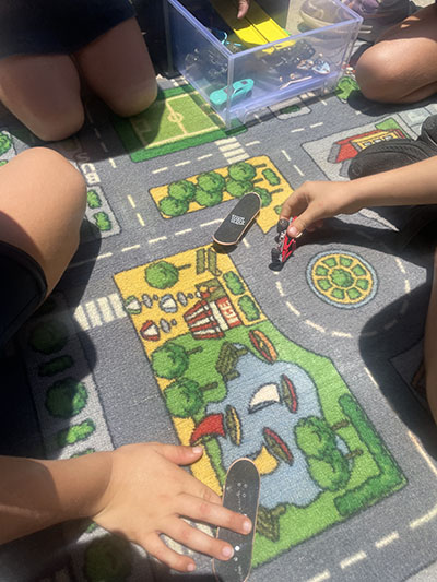 Students playing toy cars on a road map floor mat.