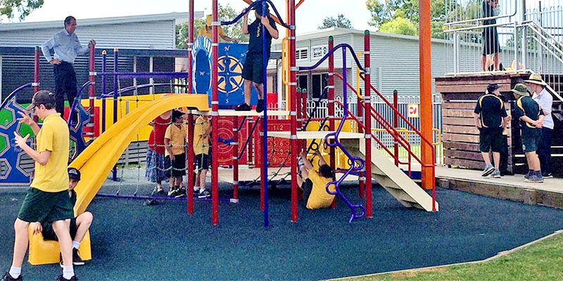 Photo of a playground with students in the court yard of a school ground